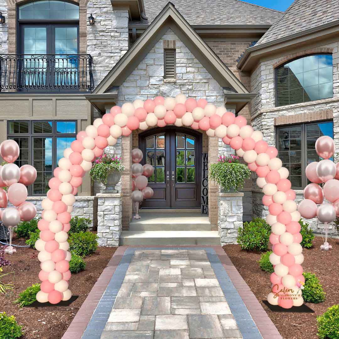Balloon arch in a swirl of pink and white and 3 sets of helium balloon bouquets decorating the front of a luxury home. Balloon decorations Salem Oregon.